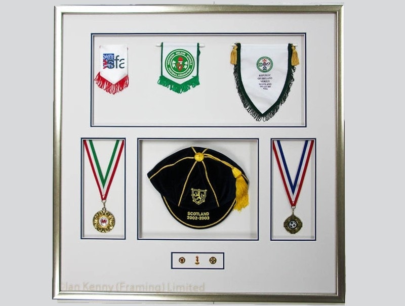 Pennants, medals, badges and an International Cap in a deep frame